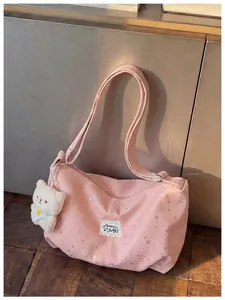 Dettaglio di borsa a tracolla in tela rosa con stelle e ciondolo orsetto di peluche.