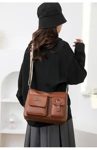 Detail view of the brown soft leather crossbody bag with multiple pockets and wide strap.