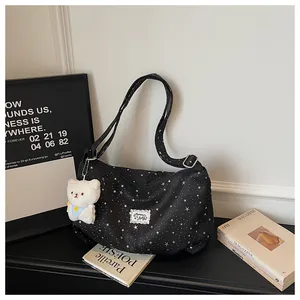 Vista dettagliata della borsa tote in tela con stampa stelle, ciondolo orsetto e bretelle regolabili.