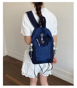 Back view of a model wearing a lightweight navy blue polka dot backpack for school