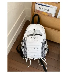 Stylish white backpack with black polka dots and gingham details in a cozy room setting