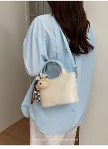 Vue détaillée du sac seau crème et bleu avec un adorable pendentif en forme d'ours