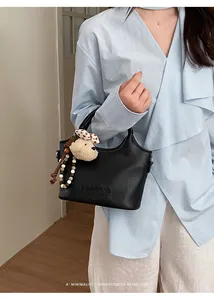 Détail d'un chic sac à main de banlieue en cuir noir avec un joli charme d'ours