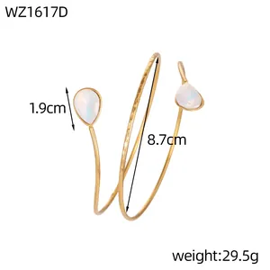Detailed macro view of gold geometric spiral arm cuff featuring pear-shaped stones