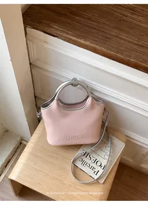 Détail d'un sac seau en cuir rose minimaliste avec poignées en métal argenté et logo PANTOR