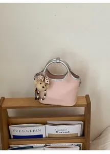 Sac seau élégant rose pour femme avec poignées argentées sur une étagère en bois