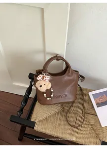 Détail d'un sac à main seau rétro marron avec un joli pendentif d'ours en peluche