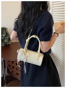 Creamy yellow cylindrical barrel handbag featuring a delicate pearl and lace bow charm