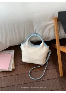 Vue détaillée d'un sac à main minimaliste crème et bleu sur un parquet en bois foncé.