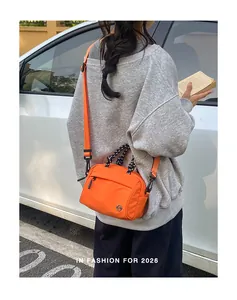Bright orange outdoor multi-functional crossbody bag shown worn by a model in a travel scene