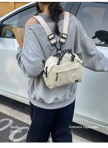 Detailed view of the cream outdoor multifunctional small backpack worn by a model