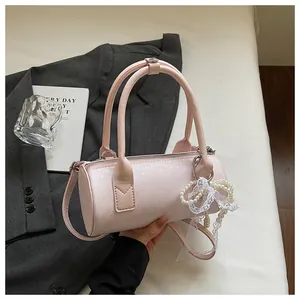 Detailed view of a pink barrel handbag with pearl lace charm and top handles