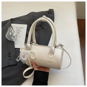 Detail view of the white barrel bag held by hand with elegant pearl charm decoration