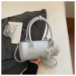 Detail view of light blue cylinder handbag featuring pearl lace charm and star pattern