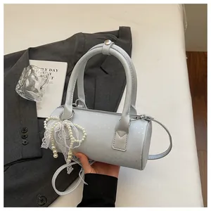 Close-up view of light blue barrel handbag featuring pearl and lace ribbon charm