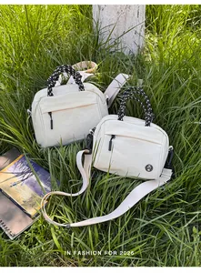 Two lightweight white canvas backpacks displayed in a green grassy outdoor setting.