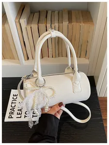 Close-up of elegant white cylindrical barrel bag with pearl bow and lace detail