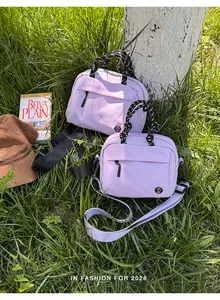 Close-up of light purple outdoor multi-functional crossbody bags with cord handles on grass