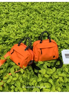 Detailed view of two orange outdoor multi-functional crossbody bags with rope handles
