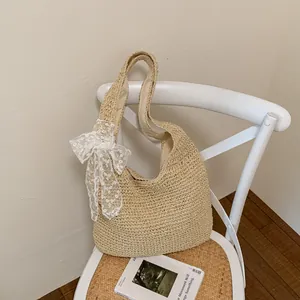 Vista detallada del bolso tote de paja tejida decorado con un elegante lazo de encaje blanco.