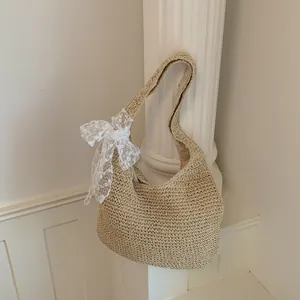 Detalle de bolso de hombro de paja de verano, elegante bolso hobo con bonito lazo de encaje blanco.