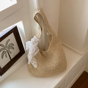 Vista detallada del bolso de hombro de paja tejida con elegante lazo de encaje blanco, beige.