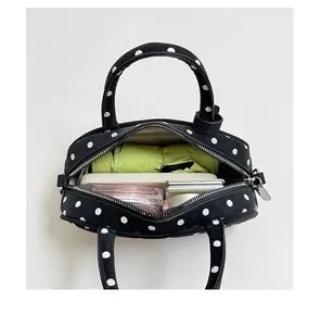 Detail view of the open black and white polka dot bowling handbag showing spacious interior storage.