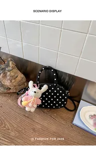 Detail view of black and white polka dot bowling bag featuring cute bunny plush charm.
