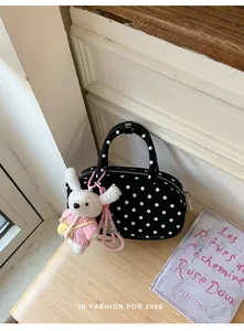 Detailed shot of black white polka dot bowling bag with cute plush rabbit charm.