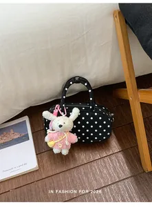Detail shot of black polka dot bowling shoulder bag with cute rabbit pendant on wooden floor.