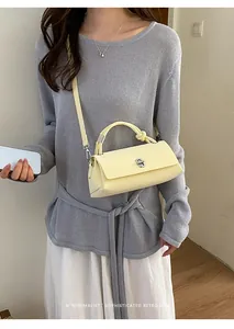 Model trägt eine elegante cremegelbe minimalistische Handtasche mit Knotengriff-Detail.