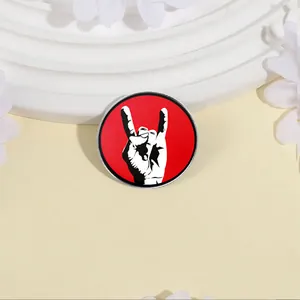Round metal brooch badge with red rock on hand gesture design