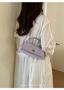 Seitenansicht einer lavendelfarbenen Handtasche getragen über weißem Trenchcoat