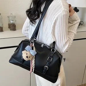 Close-up view of the black vintage shoulder bag featuring cute bear charm and bow detail.