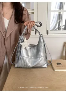 Bolso hobo plateado con textura tejida sostenido por una modelo en estilo retro