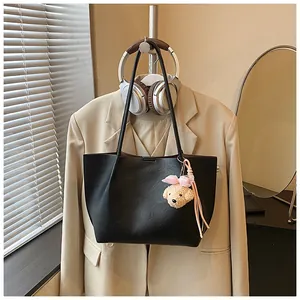 Stylish black large-capacity leather tote bag with plush charm shown in lifestyle scene