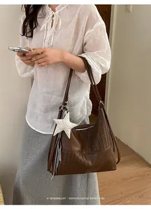 Primer plano de bolso tote tejido marrón grande con colgante de estrella estilo retro.