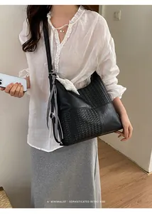 Bolso tote grande de cuero tejido negro llevado como bandolera elegante