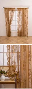 Détail de rideau transparent en dentelle française avec élégante broderie florale dorée.
