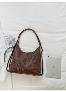 Elegante bolso hobo de mujer en patchwork tejido marrón sobre un fondo de tela
