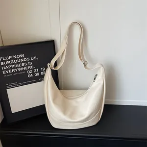 Detailed view of white crescent hobo shoulder bag, smooth PU leather texture and curved shape.