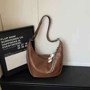 Detail view of brown PU leather hobo shoulder bag with cute charm, elegant daily dumpling bag