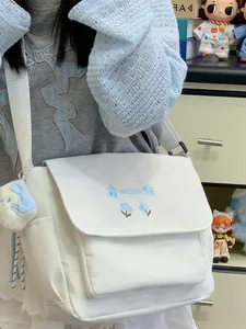 Casual white canvas crossbody messenger bag with blue floral embroidery and cute plush pendant.