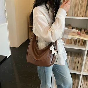 Stylish brown leather hobo shoulder bag for women, trendy dumpling crossbody bag with cute charm.