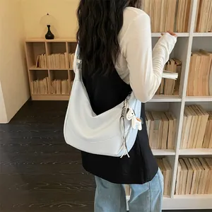 Detailed view of stylish light blue slouchy shoulder bag with cute pony charm in library.