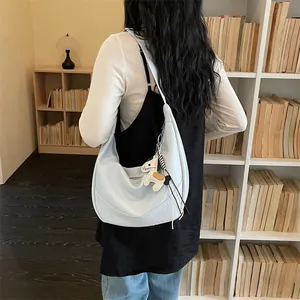 Detail shot of light blue hobo shoulder bag for women, stylish dumpling crossbody bag with cute charm.