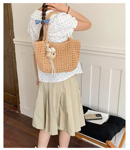 Vue détaillée d'un élégant sac à épaule en paille avec pendentif ours pour l'été.
