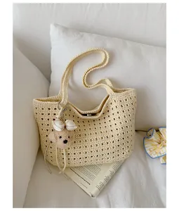 Vue détaillée d'un sac bandoulière ajouré beige avec un joli porte-clés chiot pour l'été.