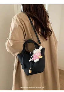 Minimalist black leather bucket bag featuring a golden padlock and cute rabbit charm