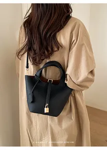 Detailed view of the chic black leather bucket handbag with gold-tone lock and straps.